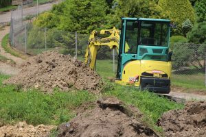 Koparka wykonująca roboty budowlane. Obok zwały ziemi.