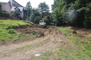 Koparka wykonująca roboty budowlane. Obok zdarta ziemia.