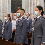 Grupa osób min. Policjantów stojących w ławkach koscielnych podczas mszy.