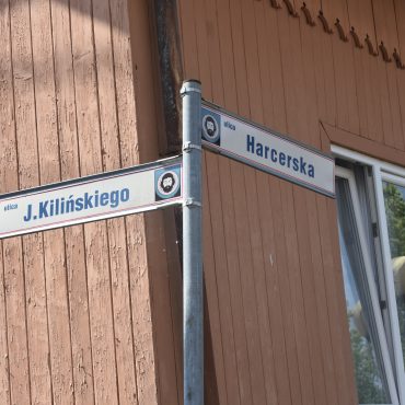 Znak drogowy. W tle drewniany budynek.