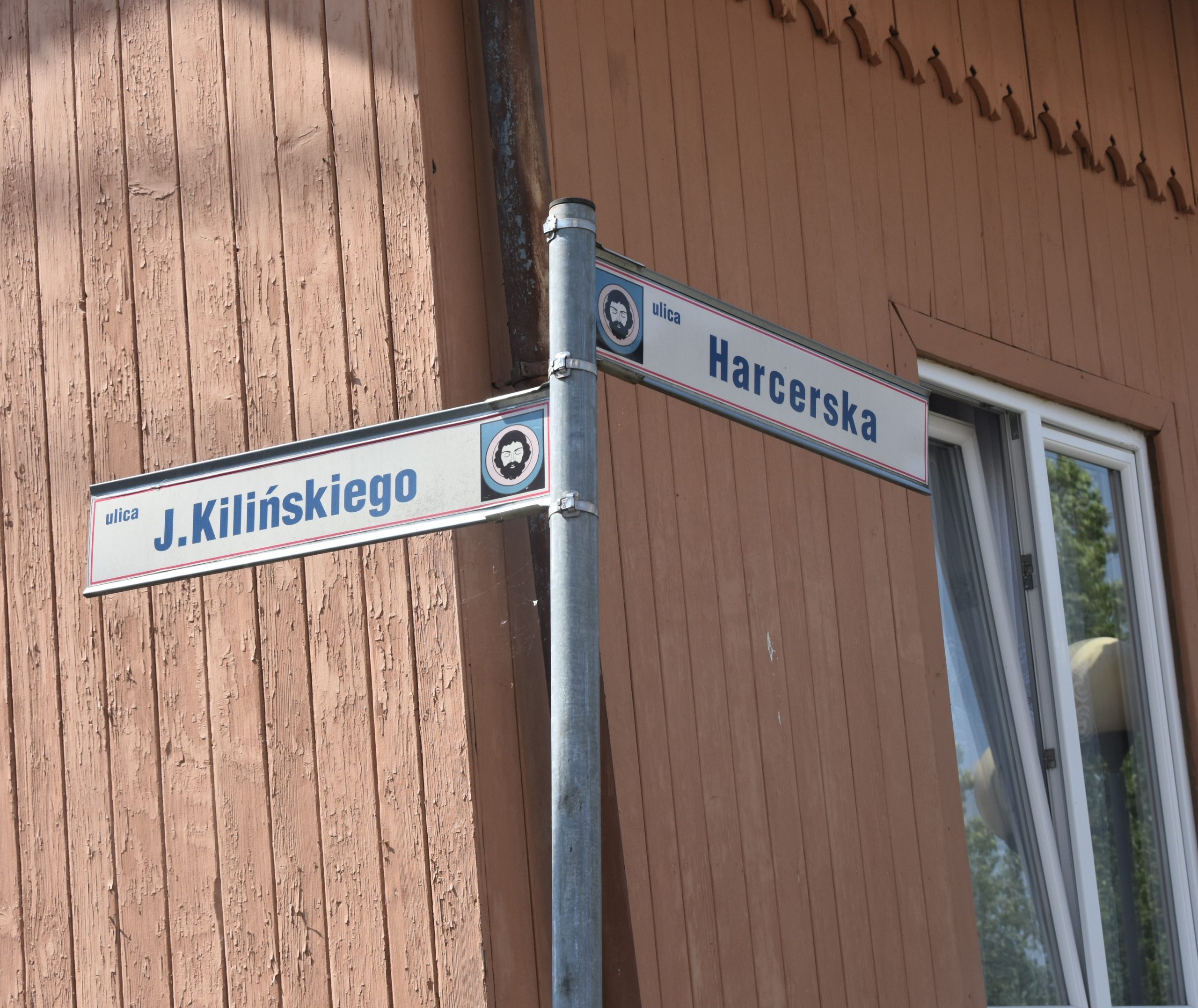 Znak drogowy. W tle drewniany budynek.