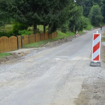 Droga z biało-czrwonymi znakami po obu stronach. W tle drzewa.