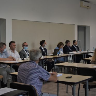 Grupa osób siedzi na sali konferencyjnej przy stolikach.