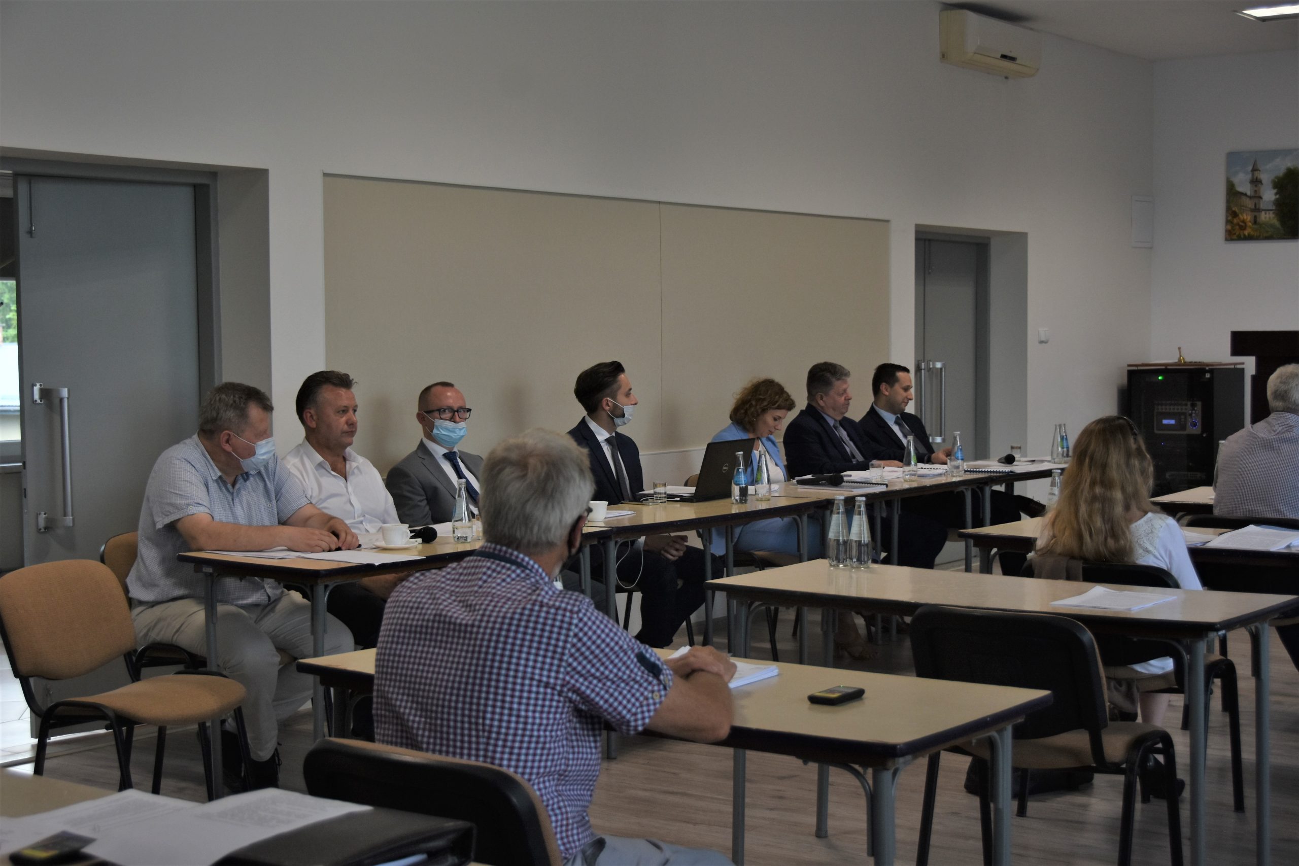 Grupa osób siedzi na sali konferencyjnej przy stolikach.