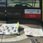 Maska starego smamochodu. Na niej mapa i ulotka.