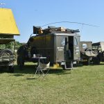 Grupa starych samochodow wojskowych zaparkownaych na łące.