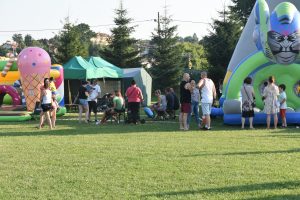 Grupa osób na imprezie. W tle dmuchańce i namiot.