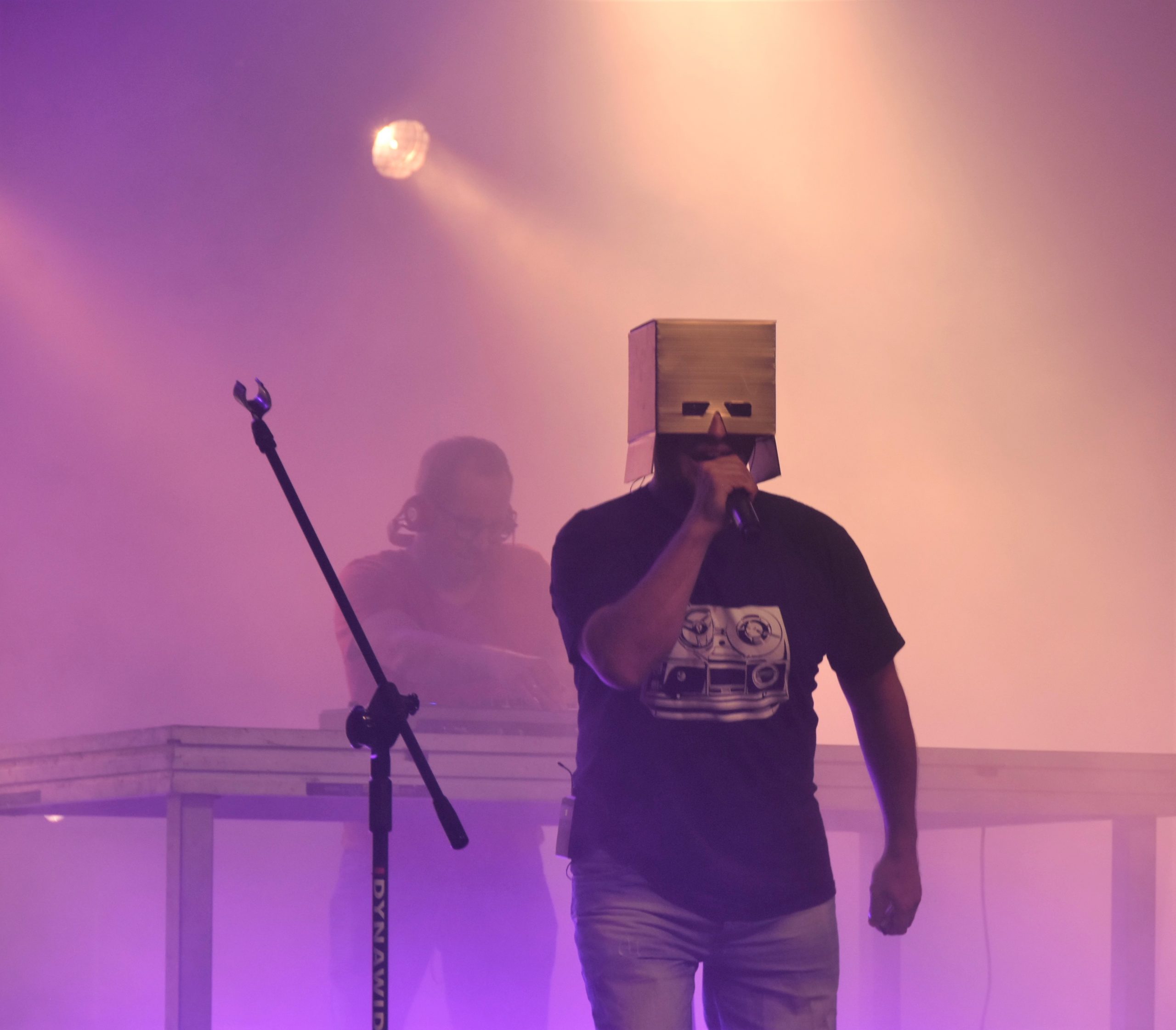 Mężczyzna z kartonem na głowie występujący na scenie.