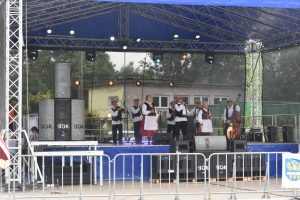 Kapela w strojach luudowych, odgrywająca występ na scenie.