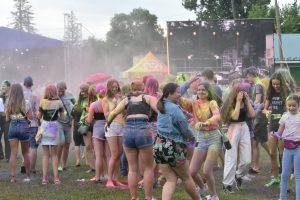 Grupa młodych osób na imprezie. Są ubrudzone kolorowymi farbami.