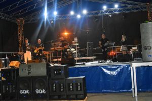 Zespół złorzony z pięciu mężczyzn i jednej kobiety, dajacy występ na scenie.