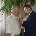 Mężczyzna w garniturze odznacza starszego mężczyzne.