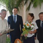 Dwóch stojacych meżczyzn w garniutrów i para starszych osób pozujaca do zdjęcia.