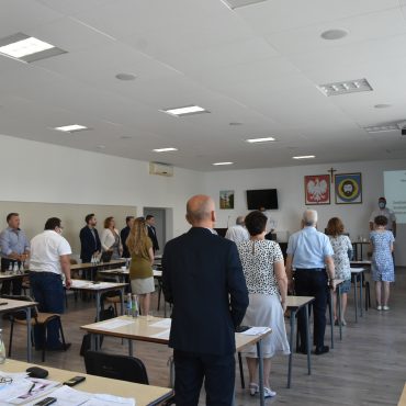 Grupa odświętnie ubranych osbó, stojąca na baczność w sali.