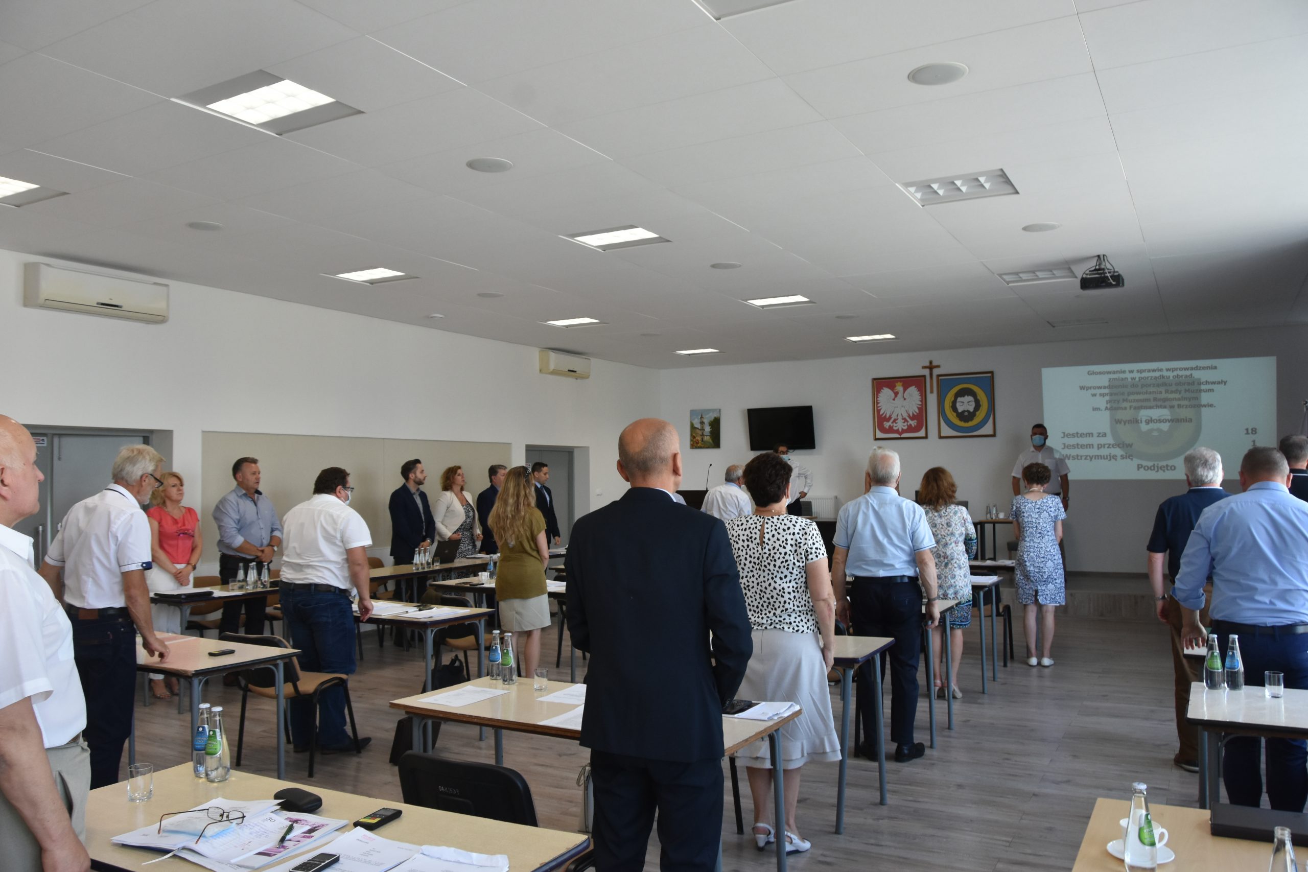 Grupa odświętnie ubranych osbó, stojąca na baczność w sali.