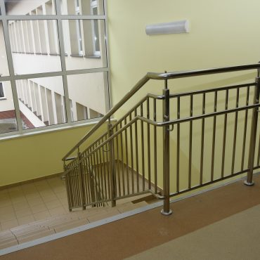 Wyremontowana klatka schodowa w szkole z nową balustradą.