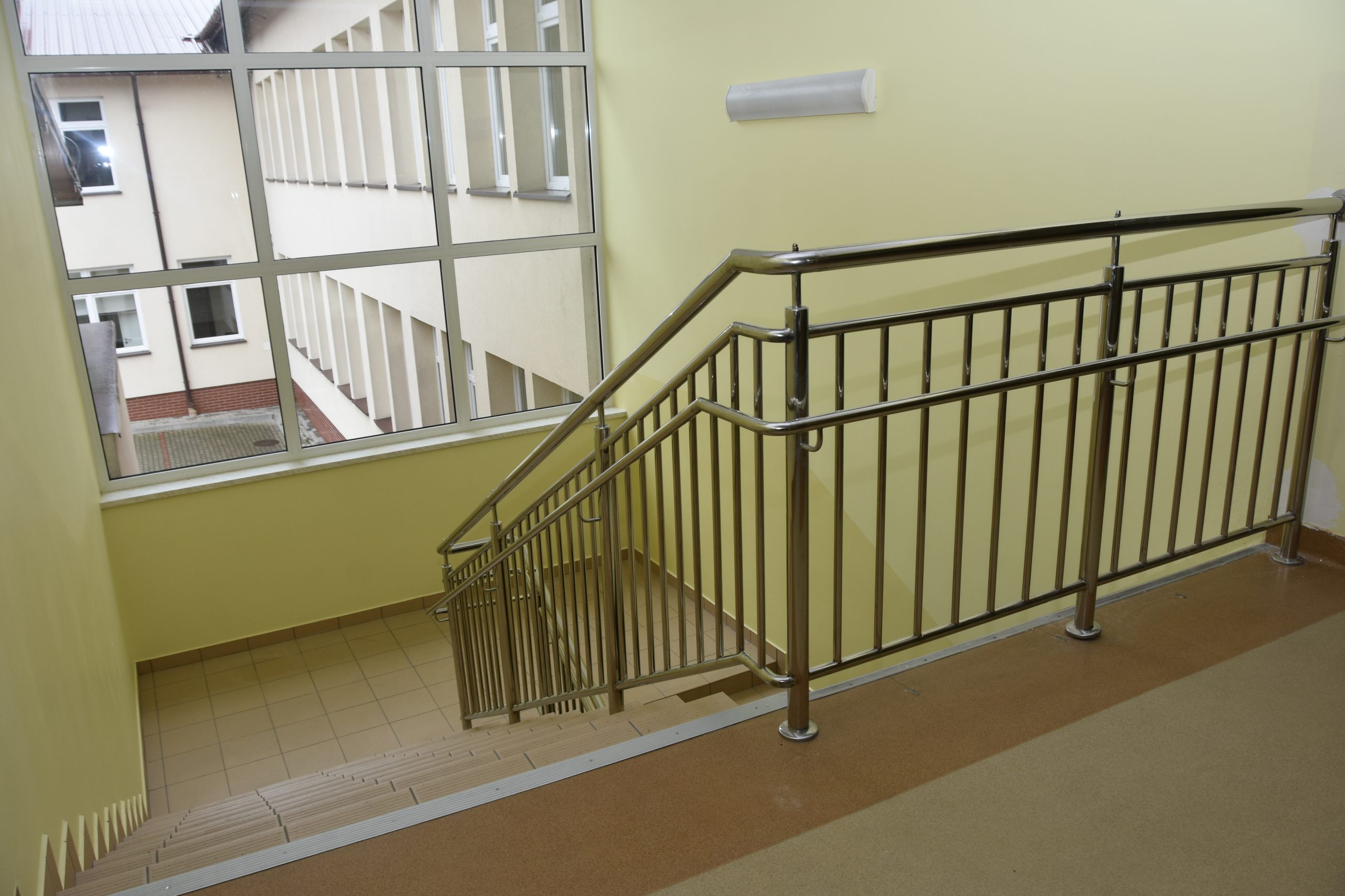 Wyremontowana klatka schodowa w szkole z nową balustradą.