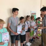 Grupa dzieci stoją przy ścianie i są dekorowanie dyplomami.