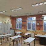 Nowo odmalowana sla lekcyjna w szkole kolotu pomarańczowego. na środku stoją stoliki i krzesełka.