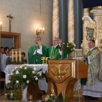 Trzech księży podczas mszy świętej w kościele stoją przed stołem głównym.