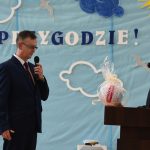 Dwóch mężczyzn w garniuturach stoją na sali gimnastycznej. jeden z nich trzyma piłkę i przekazuje drugiemu.