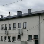 Budynek z jasną elewacją z nowymi wymienionymi oknami koloru białego.