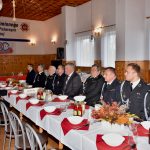 Druhowie i druhny siedzą przy zastawionym stole ubrani w mundury galowe.