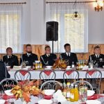 Druhowie i druhny siedzą przy zastawionym stole ubrani w mundury galowe.