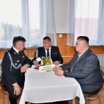 Trzej mężczyźni ubrani w mundury siedzą przy stolę i debatują.