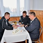 Trzej mężczyźni ubrani w mundury siedzą przy stolę i debatują.