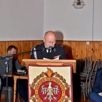 Druh ubrany w mundur galowy wstaje i przemawia przez mikrofon z mównicy.