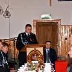 Mężczyzna ubrany w mundur galowy odczytuje sprawozdanie przez mikrofon na mównicy.