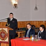 Druh ubrany w mundur galowy wstaje i przemawia przez mikrofon z mównicy.