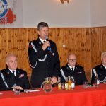 Mężczyzna ubrany w mundur galowy wstaje i przemawia przez mikrofon.