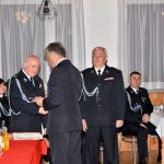 Mężczyzna ubrany w mundur galowy składa podziękowania dwóm starszym