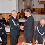 Mężczyzna ubrany w mundur galowy składa podziękowania dwóm starszym