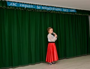 Dziewczynka w czerwonej sukience śpiewa podczas występu "ABC empatii, bo wszyscy jesteśmy tacy sami"