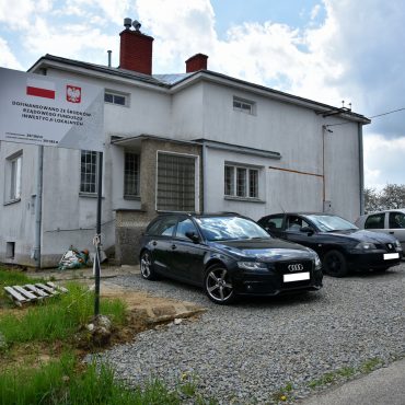 Zdjęcie białego budynku z parkingiem na sprzedaż
