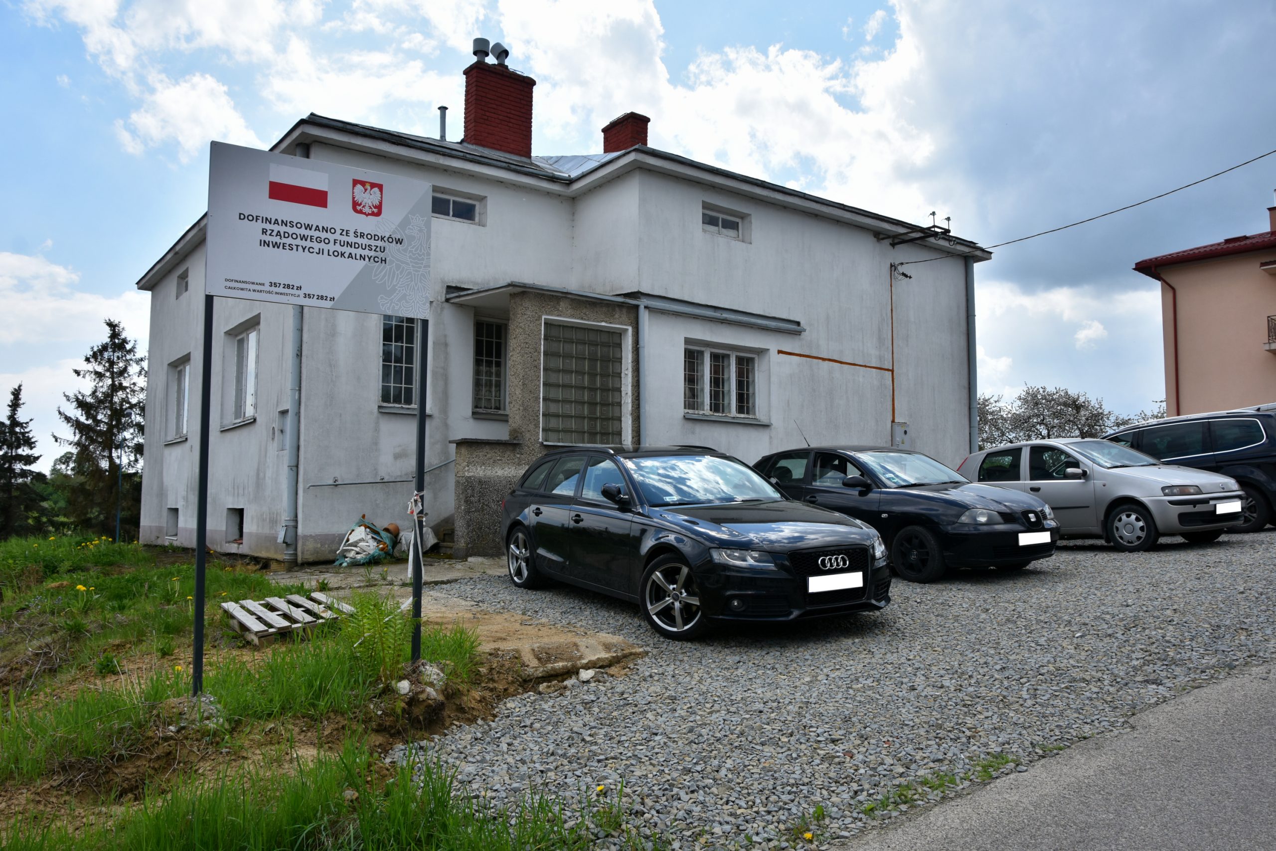 Zdjęcie białego budynku z parkingiem na sprzedaż