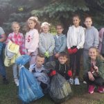 Grupa dzieci (chłopców i dziewcząt), pozujących do fotografii z wypełnionymi workami na śmieci.