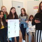 Grupa sześciu nastolatek w klasie. jedna z nich trzyma baner z napisem Violet.