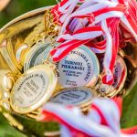 Medale złote z taśemkami biało czerwonymi, leżą w złotym pucharze.