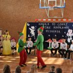 Dzieci na sali gimnastycznej w przedstawieniu artystycznym. Ubrane w odświętne białe stroje oraz stroje wróżek i skrzatów.