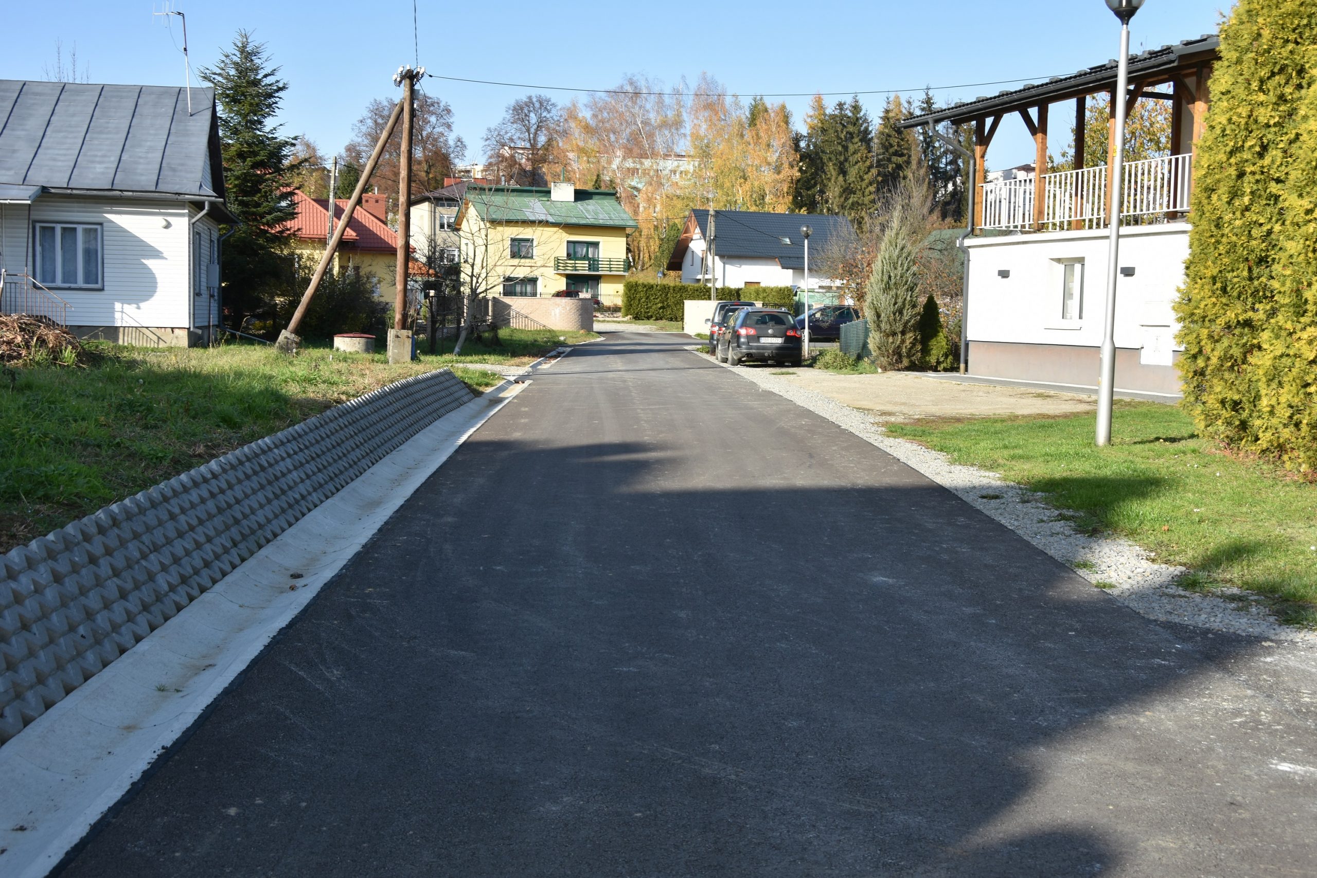 Droga z nową nawierzchnią asfaltową, miedzy budynkami.