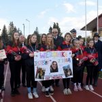 Grupa osób trzymająca baner, stojąca na stadionie.