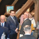 Grupa elegancko ubranych osób rozmawia i podziwia obrazy.