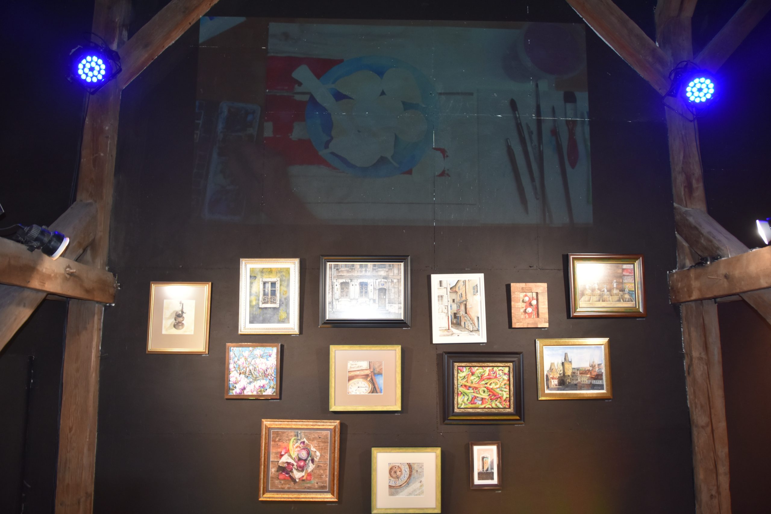 Grupa kilkunatu obrazów średniej wielkości powieszonych na ścianie.