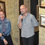 Kobieta i mężczyzna w średnim wieku stojący obok siebie. Mężczyzna przemawia za pomocą mikrofonu.