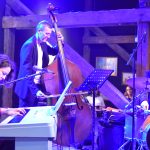 Zespół muzyczny wykonujący utwór. Grupa składa się z kobiety i dwóch mężczyzn, wszyscy są elegancko ubrani.