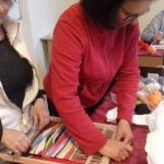 Starsza kobieta w czerwonej bluzce tkana na sprzęcie tkackim obraz.